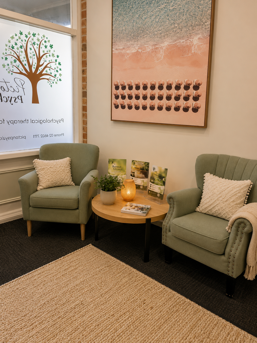 The Picton Psychology waiting room with soft green armchairs, warm lamplight and a jute rug